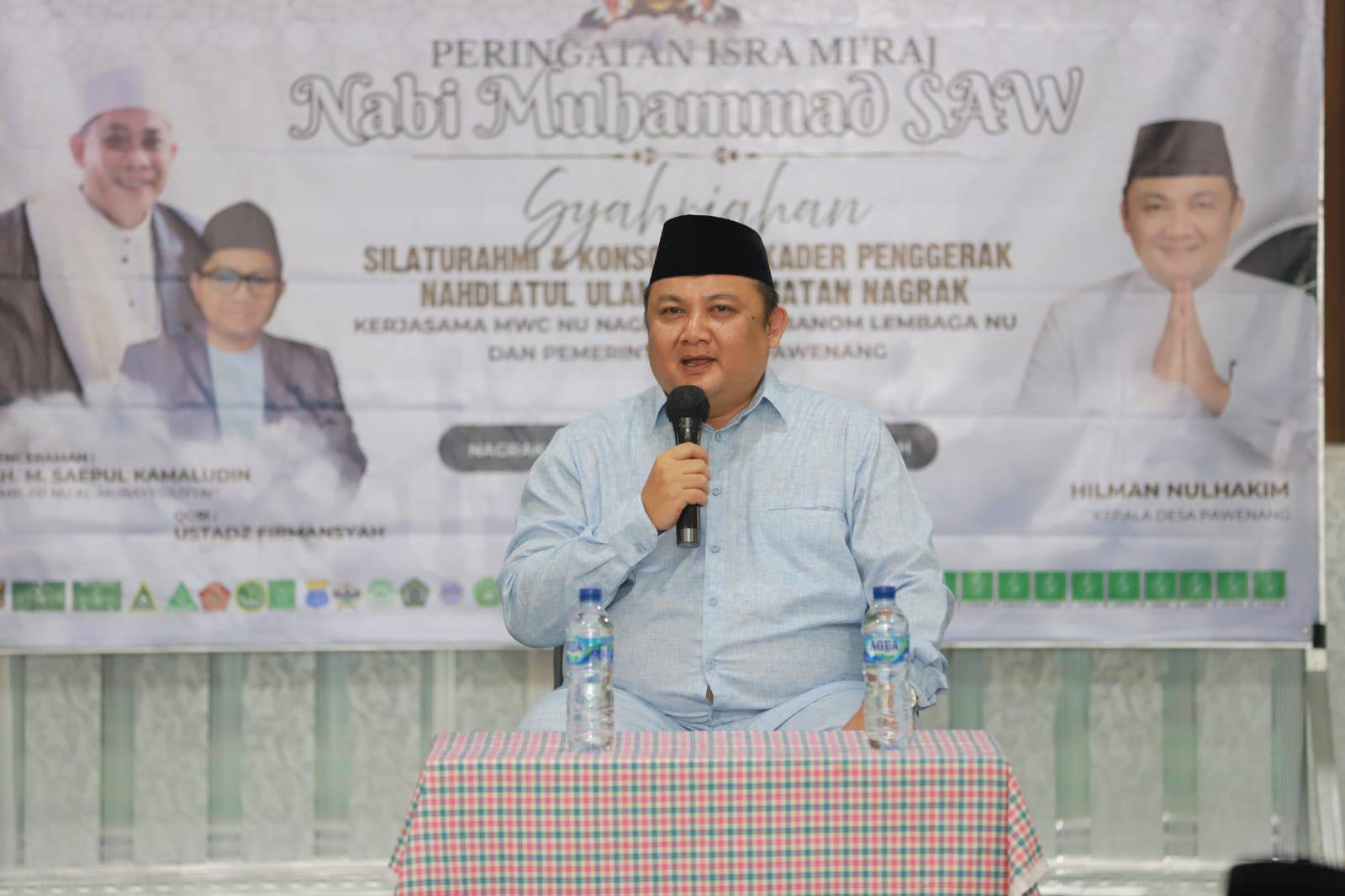 Kepala Desa Pawenang Hilman Nulhakim menghadiri peringatan Isra Miraj Nabi Muhammad SAW dan silaturahmi Alumni PD-PKPNU MWC NU Nagrak. Ia menekankan pentingnya disiplin pemerintahan dan pelayanan publik demi terwujudnya Sukabumi Mubarokah.